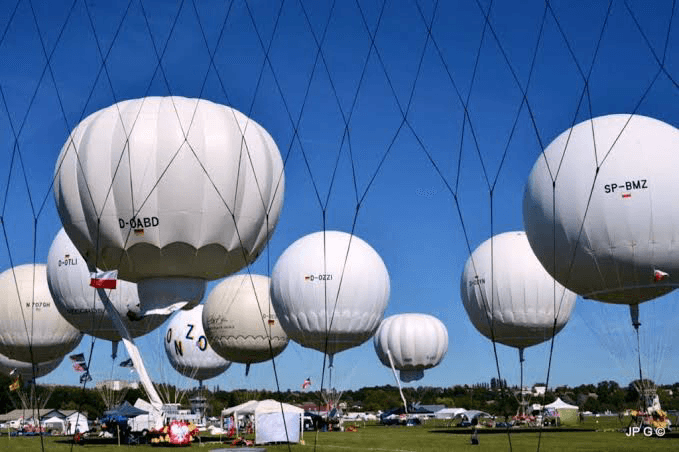 Gordon Bennett Cup gas balloons tethered under anti-collision netting at a launch field